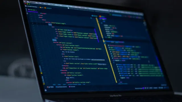 Laptop showing colourful source code, representing API endpoints under security testing