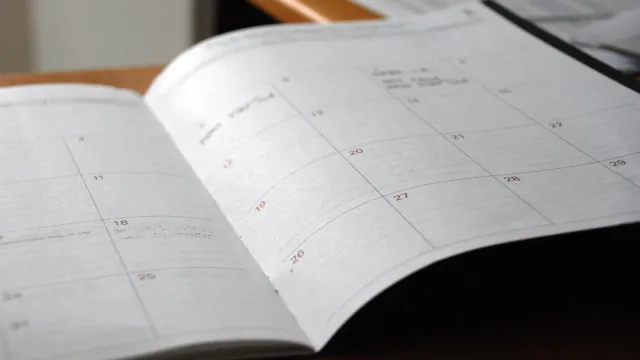 Open monthly planner on a wooden desk, representing a penetration testing schedule
