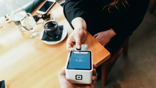 Card payment terminal held over a counter, representing systems in the PCI DSS cardholder data environment
