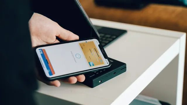 Person holding a smartphone over a card reader to make a contactless payment